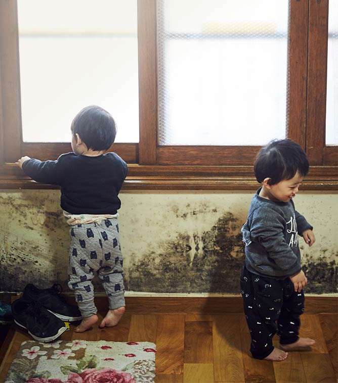 곰팡이 가득 핀 집 안에서 놀고 있는 아이들 사진